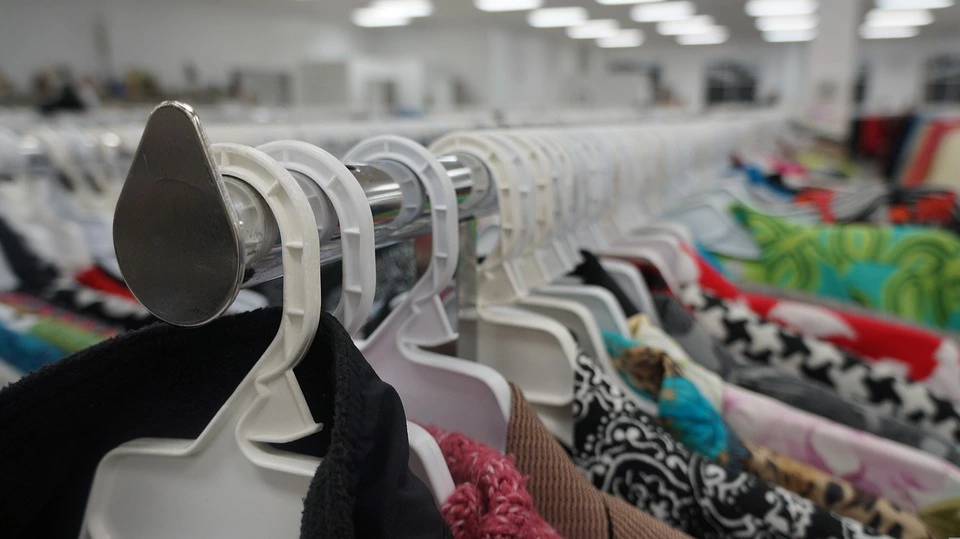 A long rack of clothing for sale at a thrift store so it can see second and third lives before being discarded.