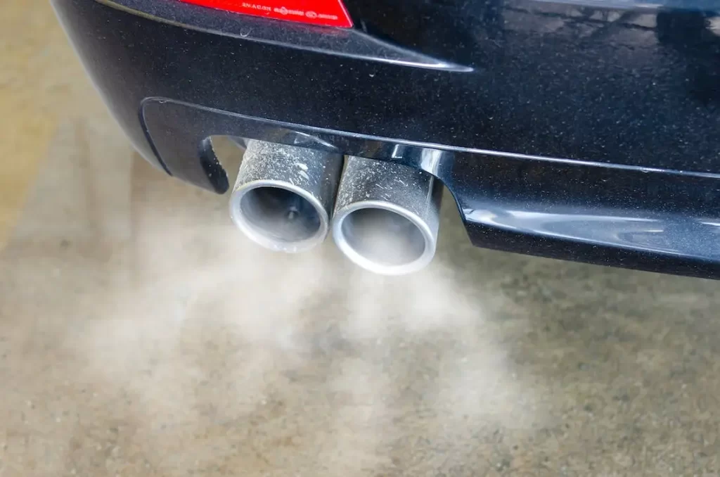Car tailpipes emit clouds of exhaust which emit carbon monoxide pollution into the atmosphere.