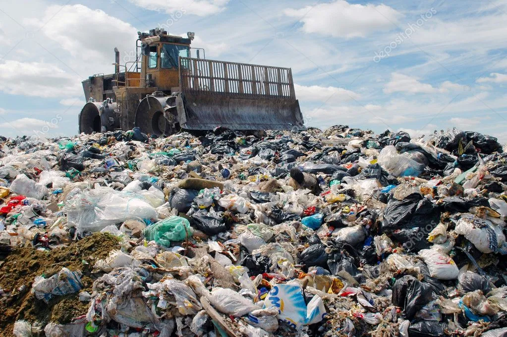 A bulldozer pushing around garbage in a landfill. Landfill mass can be reduced by recycling paper products.