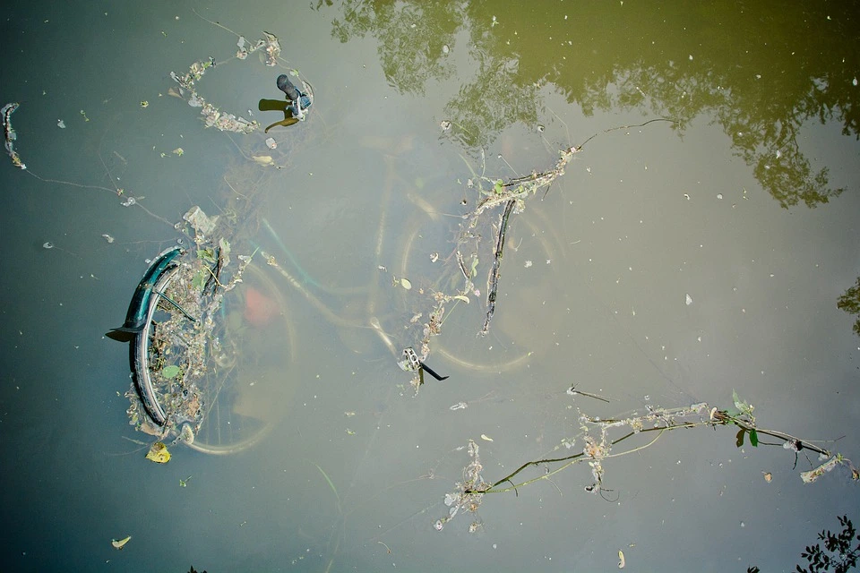 A sunken bicycle in a pond of water polluted by industrial waste.