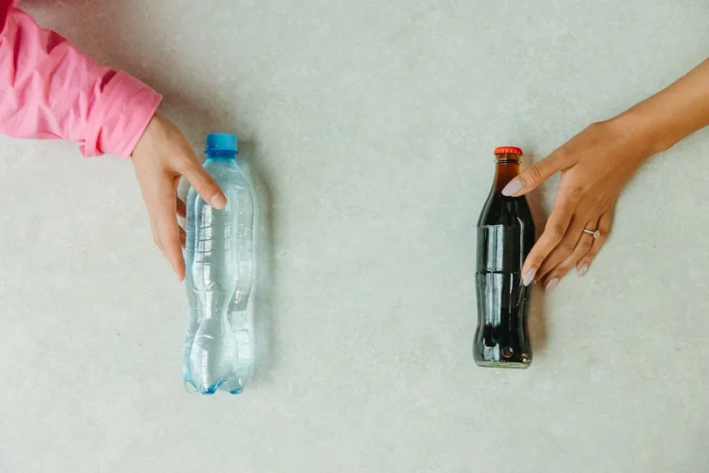 A plastic bottle and a glass bottle that can each be recycled to make new bottles.