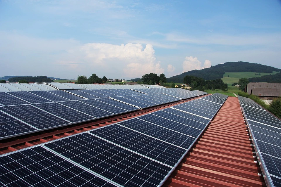 Solar panels are installed on a long metal roof.