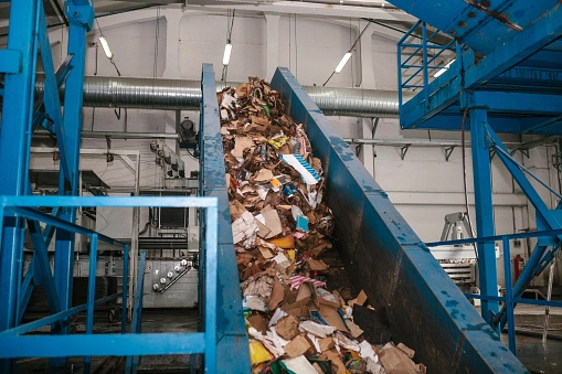 Recyclable materials going up a conveyer belt in a recycling plant.