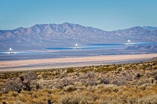 Three solar concentrators in the desert use mirrors to focus solar radiation onto a receiver.