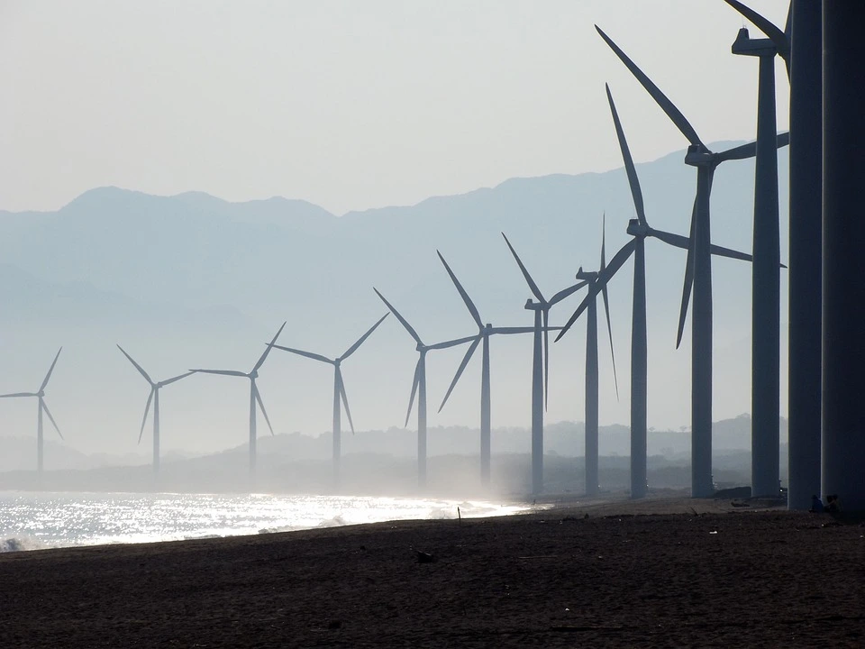 A wind farm located on the shores of the ocean catches the prevailing off-shore wind and converts it to electricity.